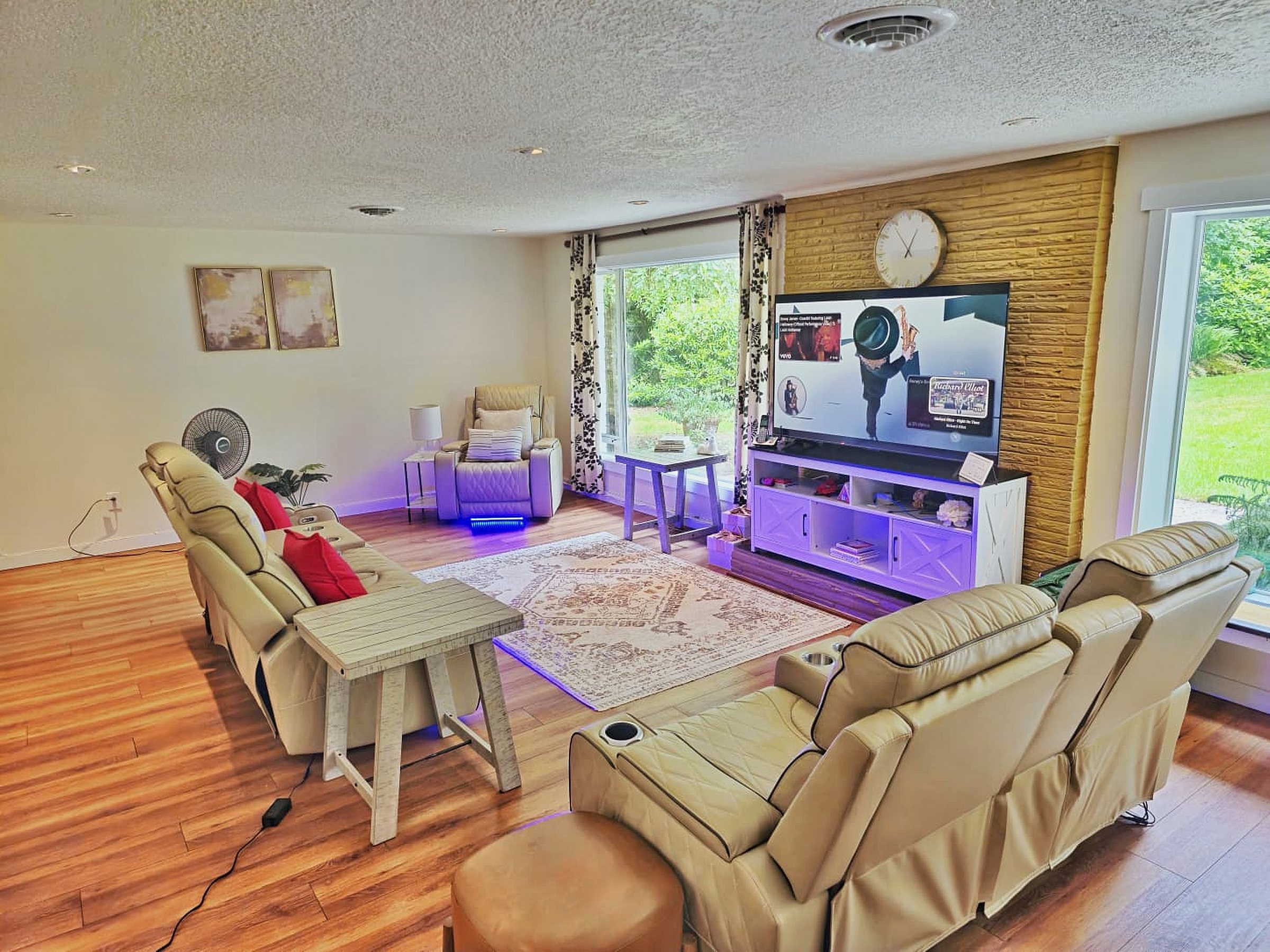 Bright living room with recliners, a large television and garden views